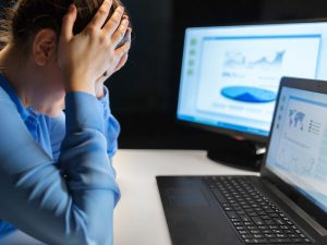 woman next to computer screens with headache